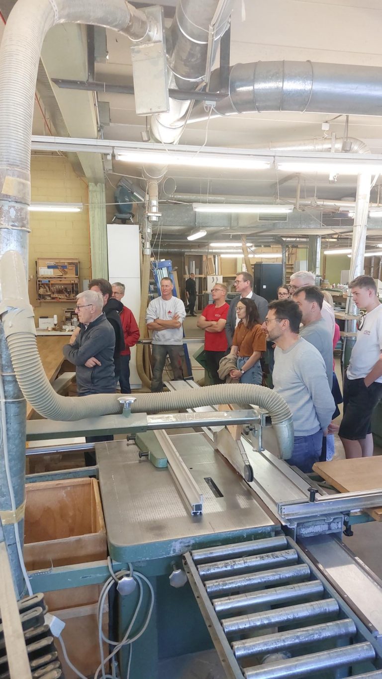 Unternehmensvorstellung Sokol Küchen Hausen Gruppe von Menschen in einer Werkstatt, die sich um eine Maschine versammelt haben.
