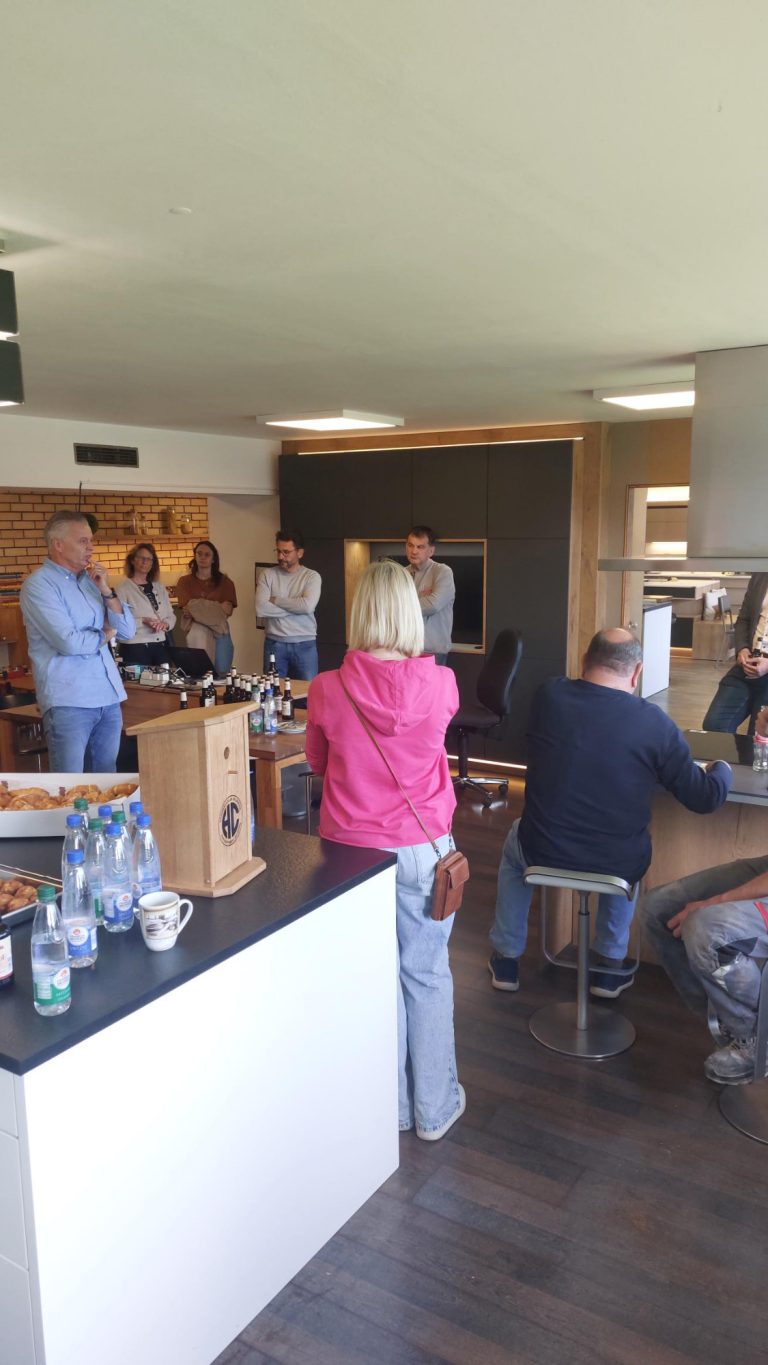 Unternehmensvorstellung Sokol Küchen Hausen Eine Gruppe von Menschen versammelt sich in einem modernen Raum mit Sitzgelegenheiten.
