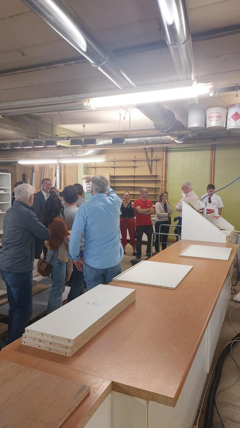 Unternehmensvorstellung Sokol Küchen Hausen Menschen in einer Werkstatt, die an einer Holzverarbeitungsschulung teilnehmen.